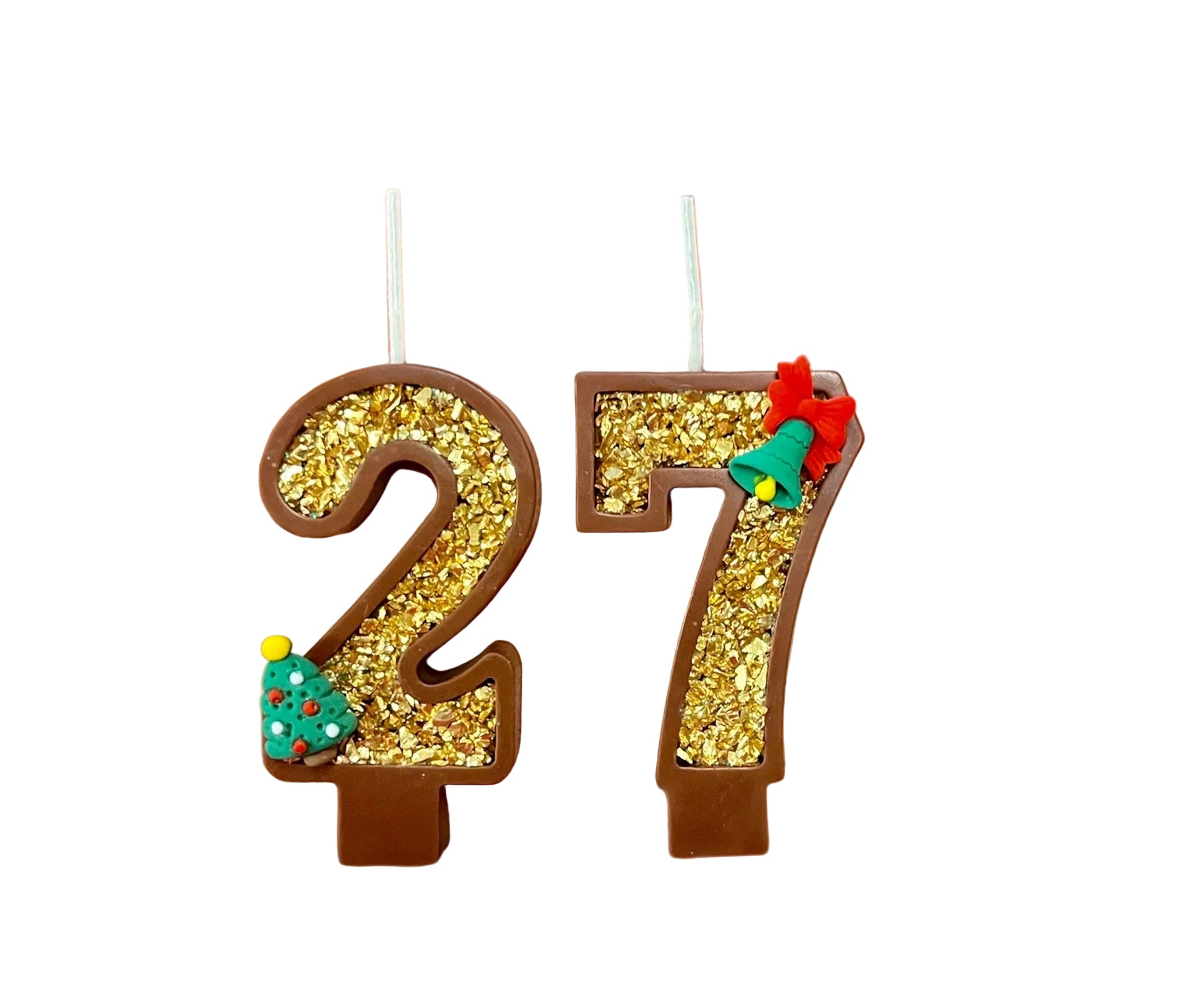 Hand holding Christmas-themed number candles '27' against a pink background